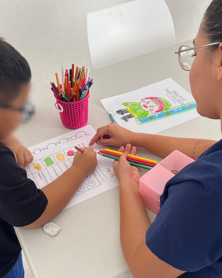 Instructora de PASOS coloreando junto a un niño en la mesa de trabajo