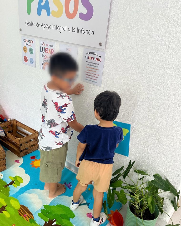 Dos hermanos frente al muro de mentalidad de crecimiento en la entrada de PASOS
